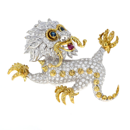 Gold and silver dragon-shaped jewelry piece with gemstones on a white background