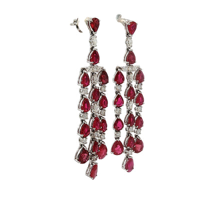 Side profile of 18 karat white gold articulated ruby and diamond chandelier earrings showing open gallery construction and pear-shaped rubies.